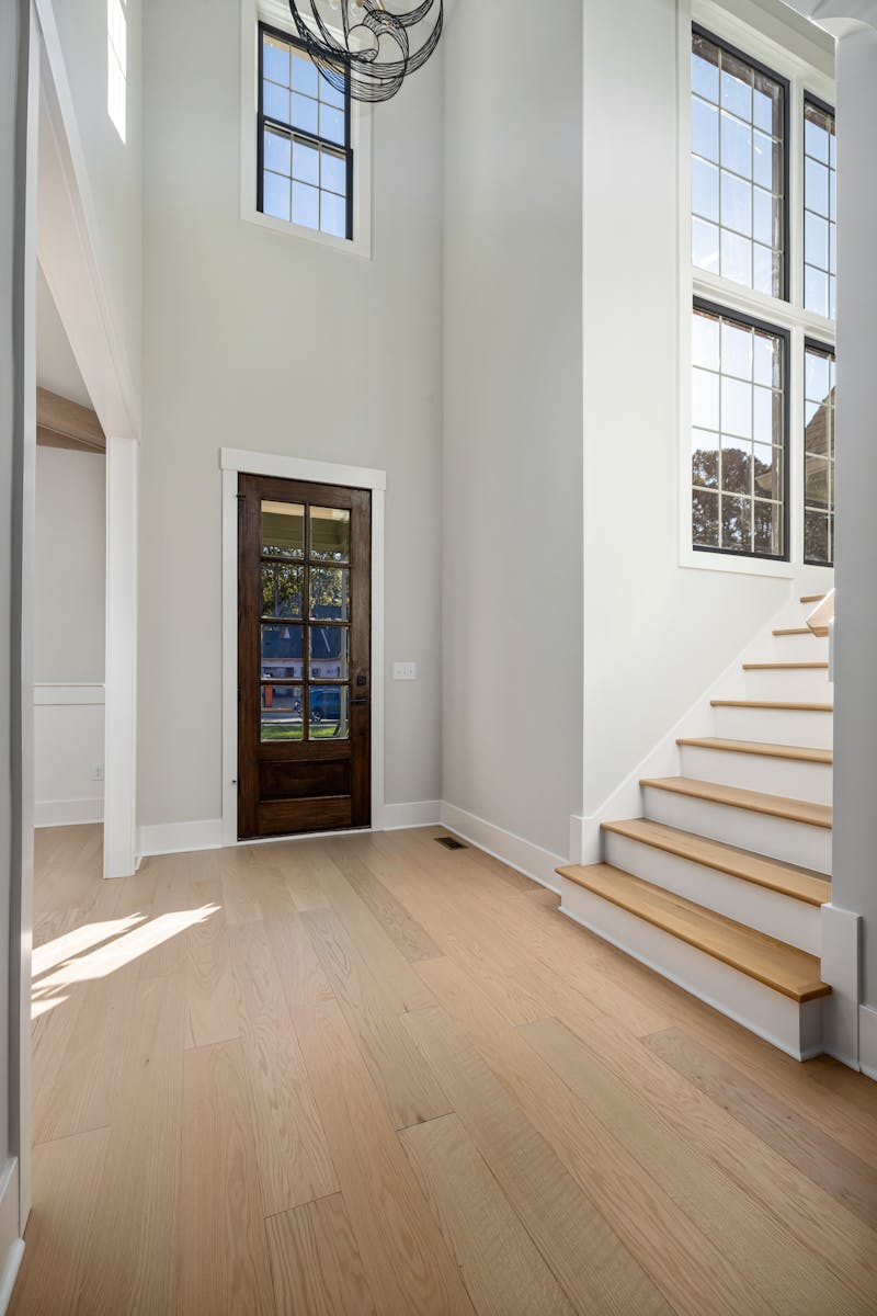 Bright and spacious home entryway featuring wooden flooring and large windows.
