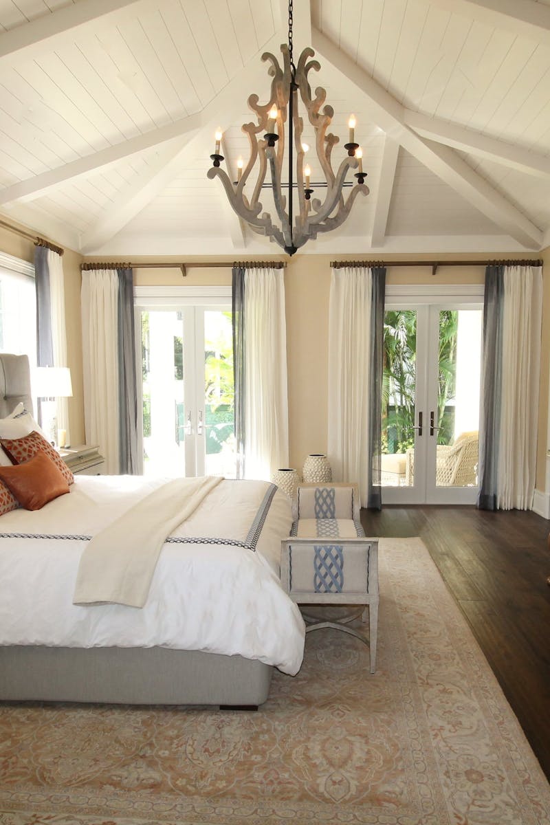 Stylish bedroom interior featuring a rustic chandelier, cozy bedding, and elegant wooden furniture.