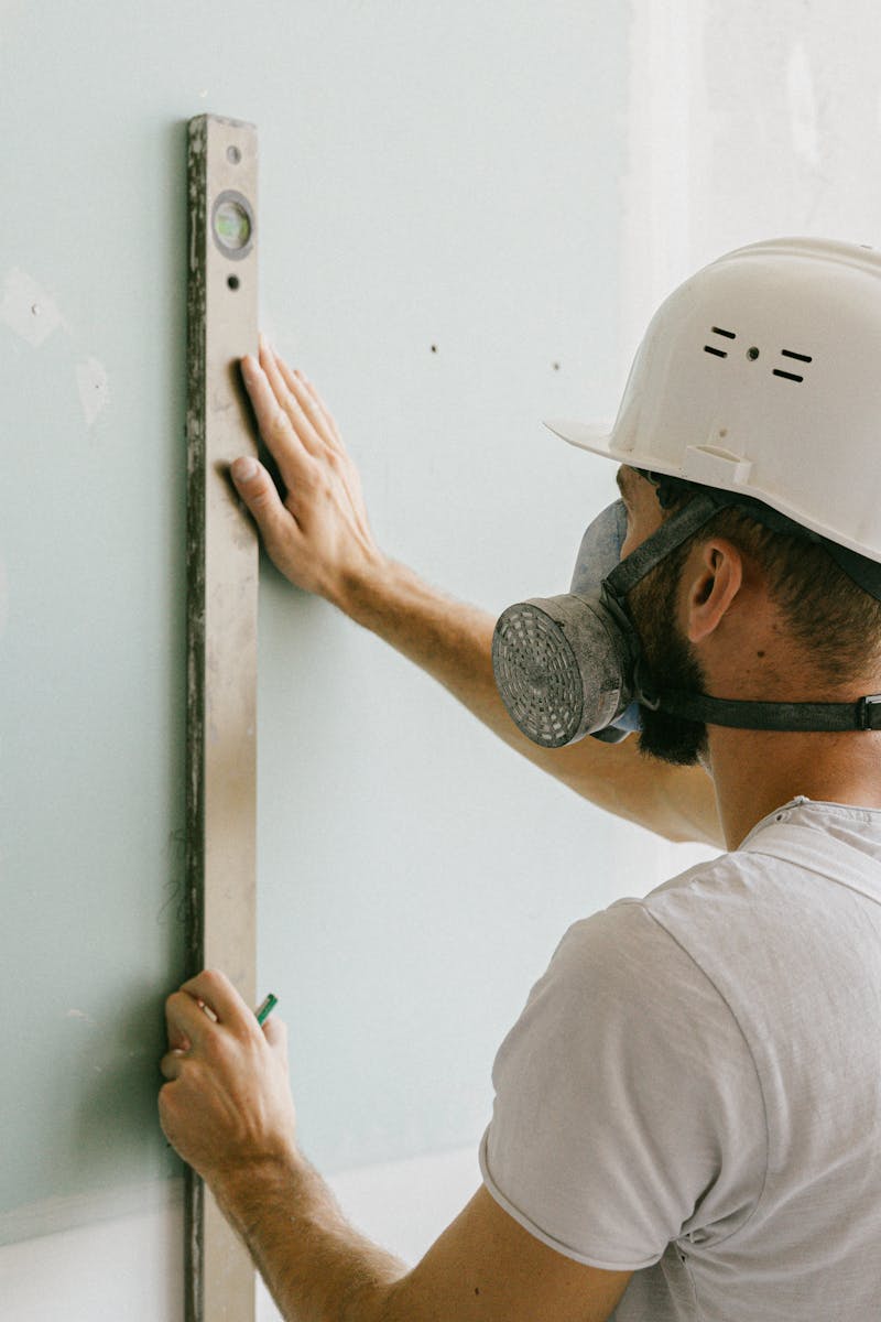 A construction worker using a leveler to ensure wall accuracy, showcasing precision.